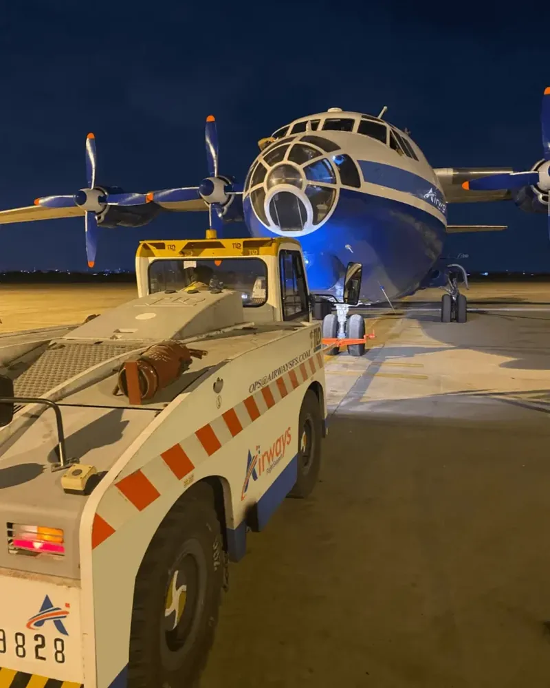 Airways slot coordination: a turboprop with a pushback tug on a lit apron